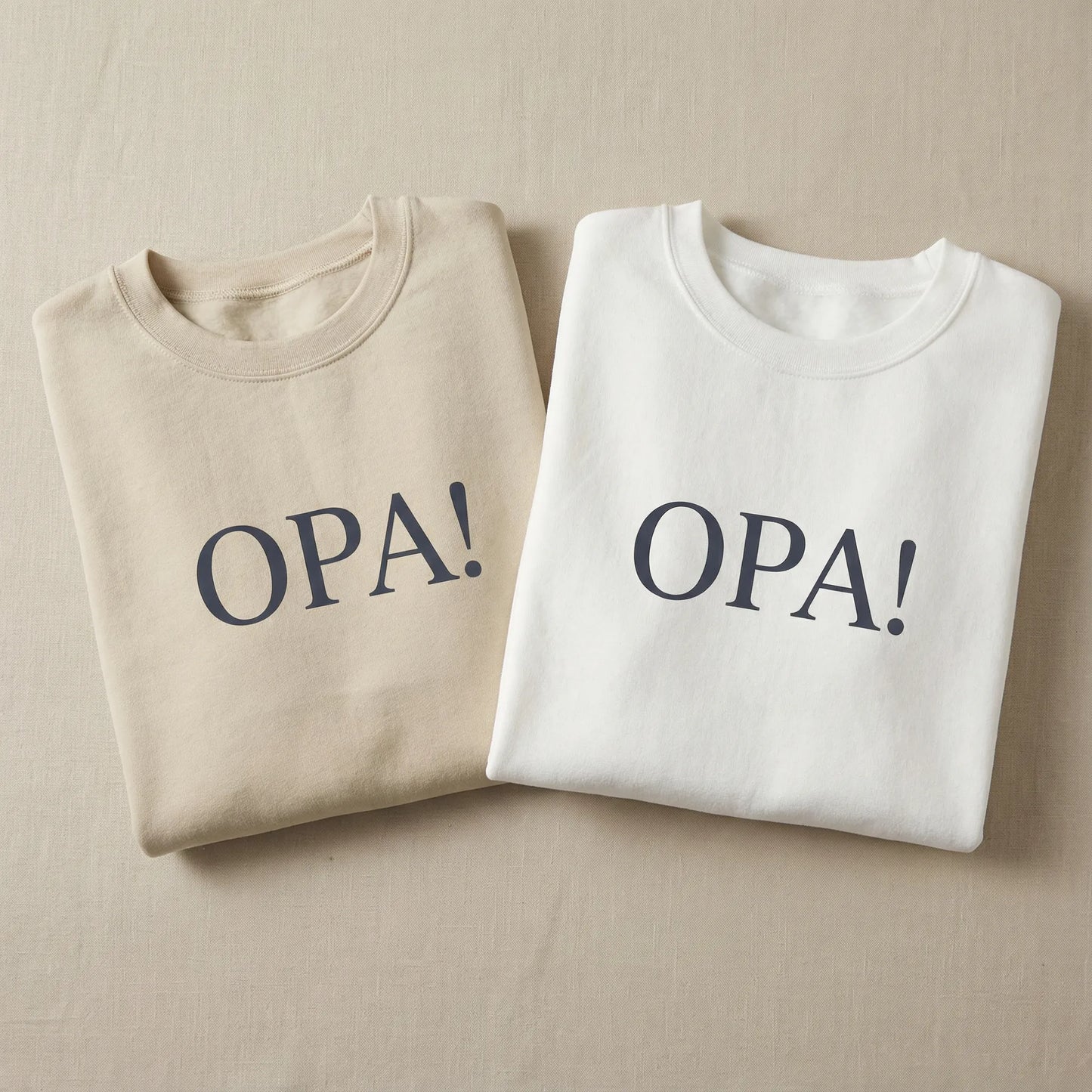 White and sand Celebratory OPA crewneck sweatshirts laid flat with identical OPA front print