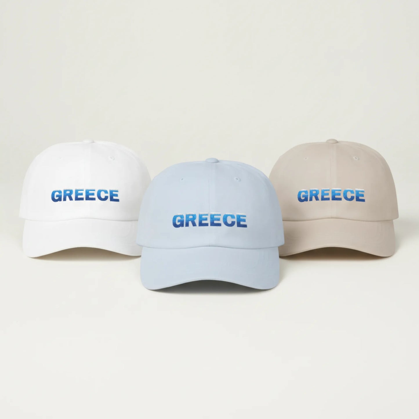 White, sand and light blue Greece Classic embroidered dad caps arranged side by side