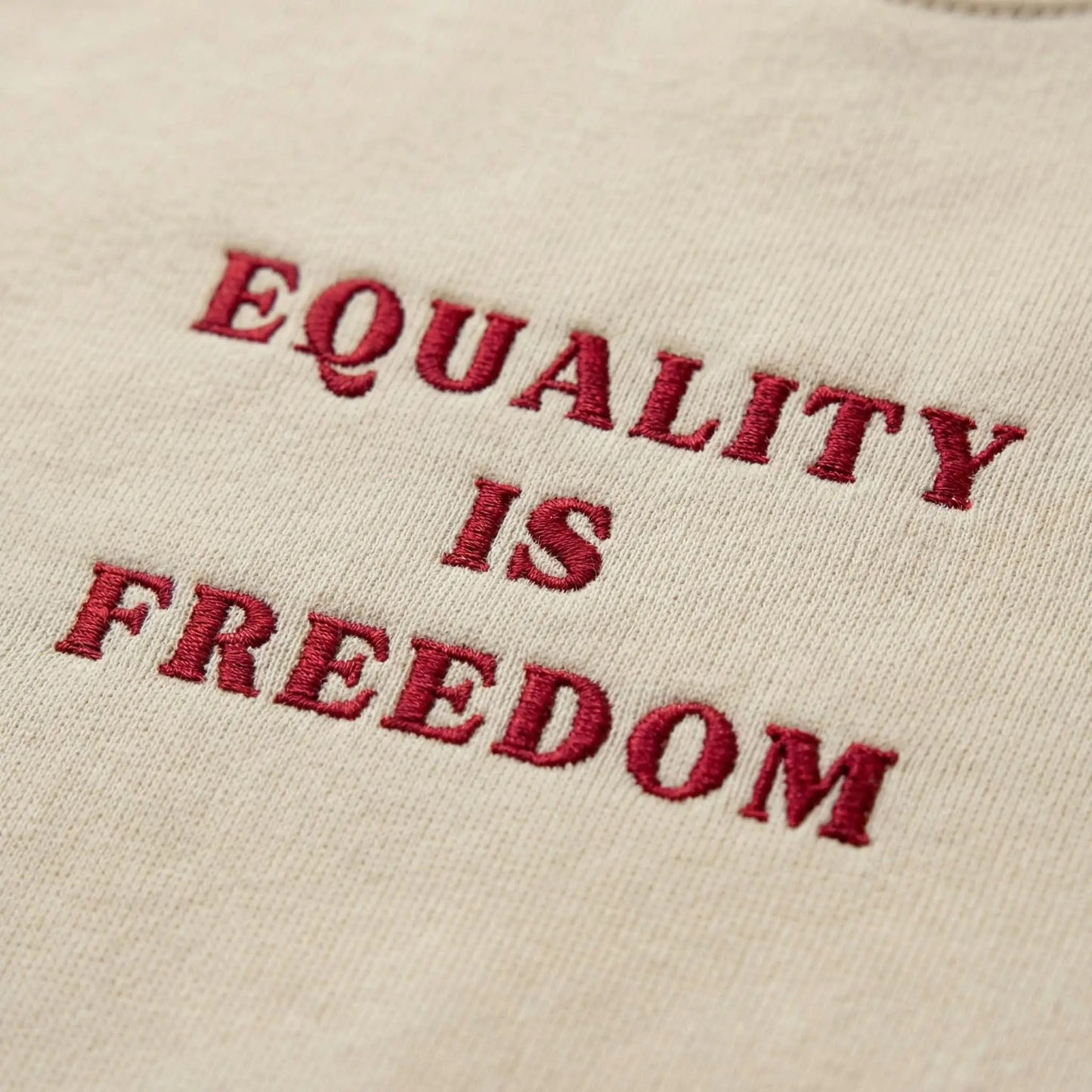 Close-up of deep red Equality Is Freedom embroidery on Sand fleece