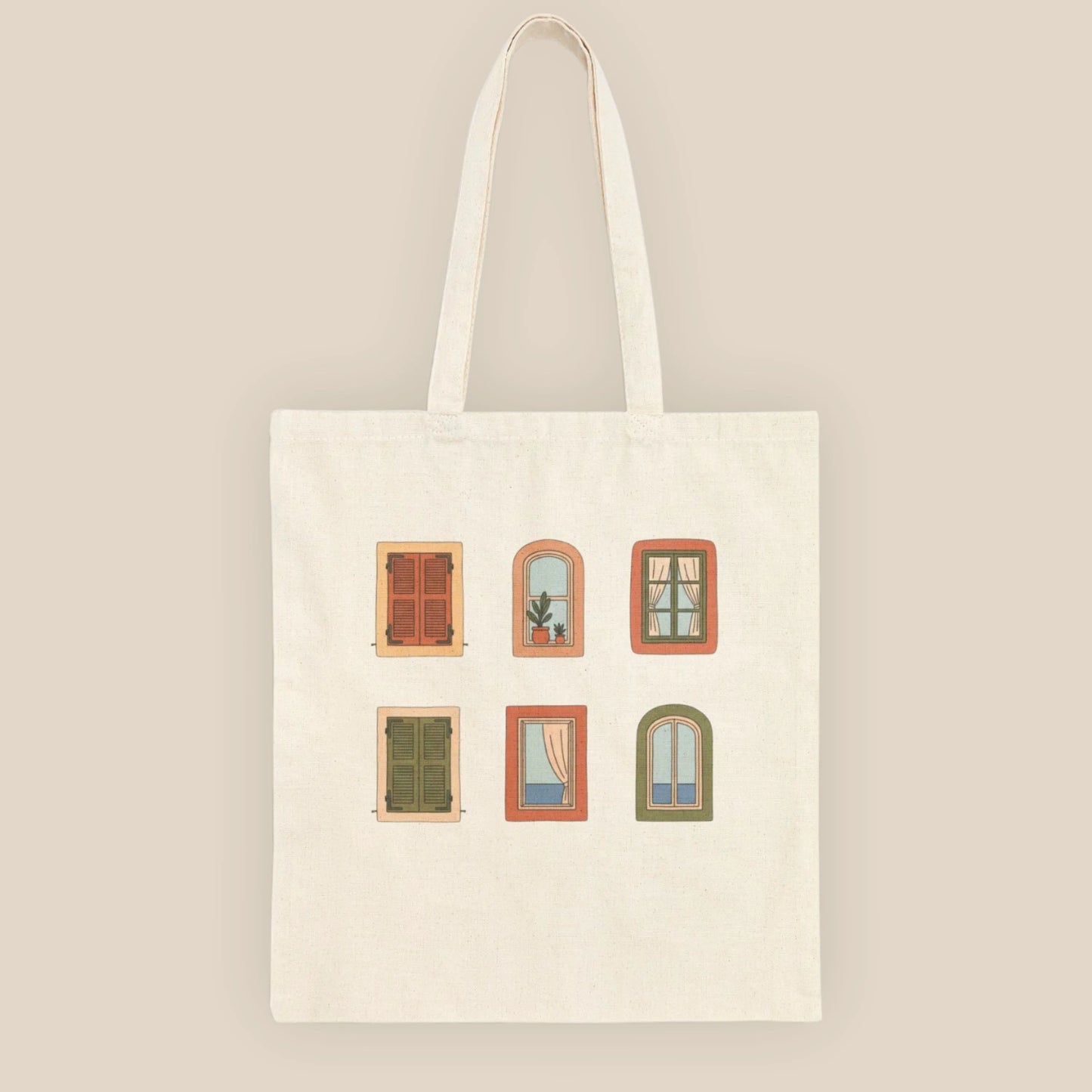 Top-down flat lay of the Mediterranean Windows natural cotton tote bag on a neutral beige fabric surface