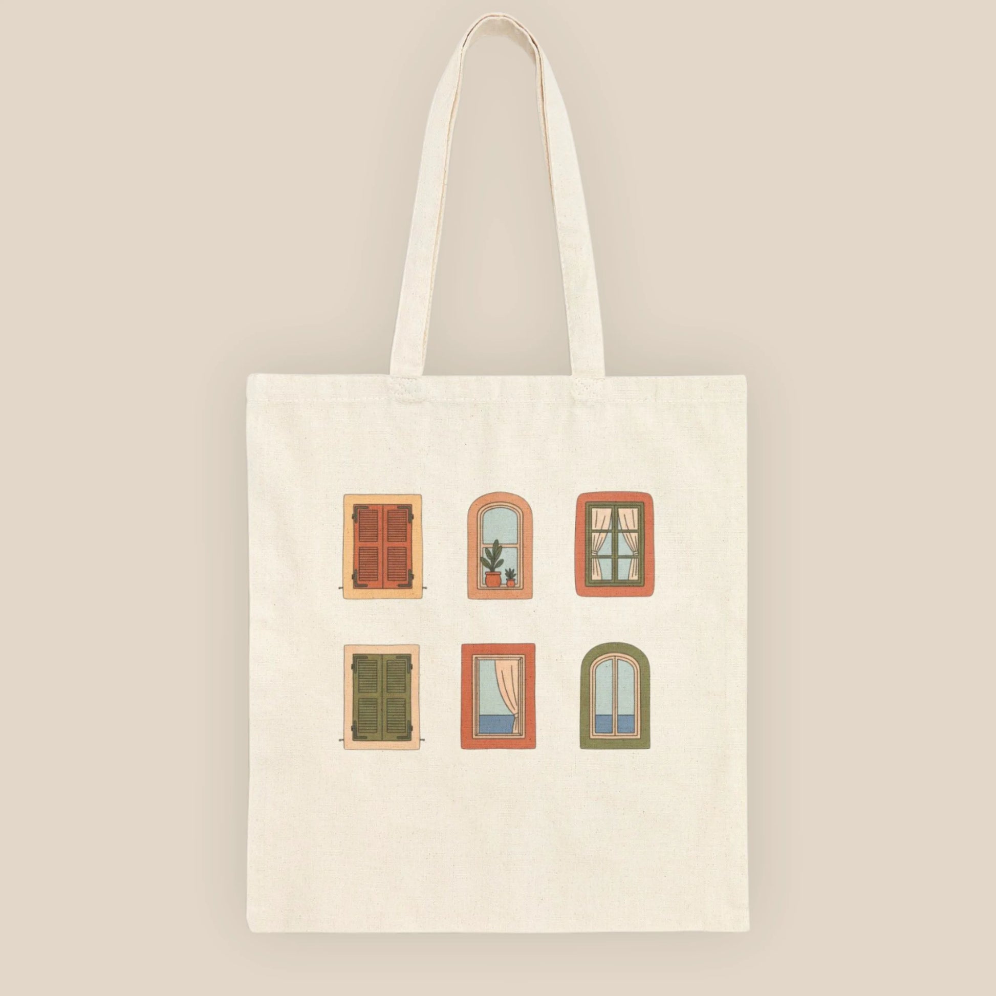 Top-down flat lay of the Mediterranean Windows natural cotton tote bag on a neutral beige fabric surface