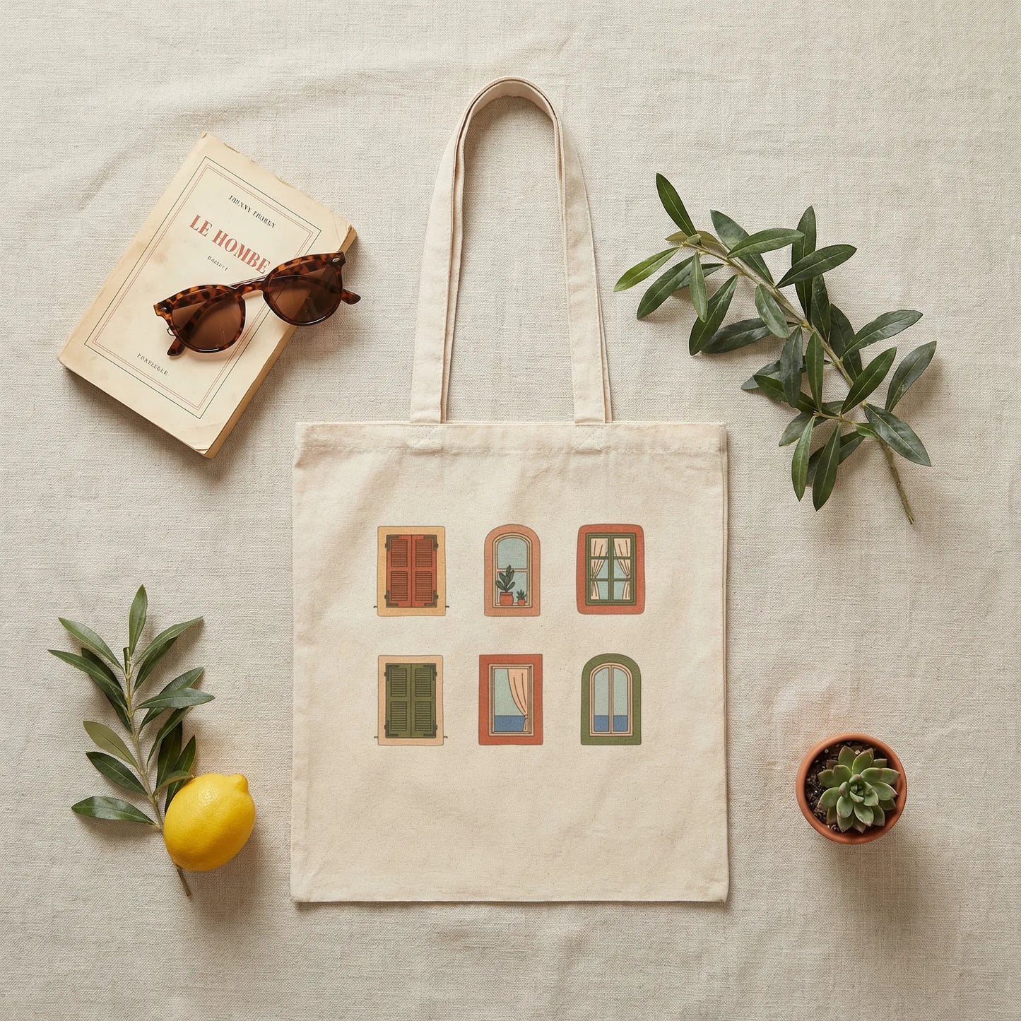Flat lay of Mediterranean Windows tote with books and accessories on a neutral surface.