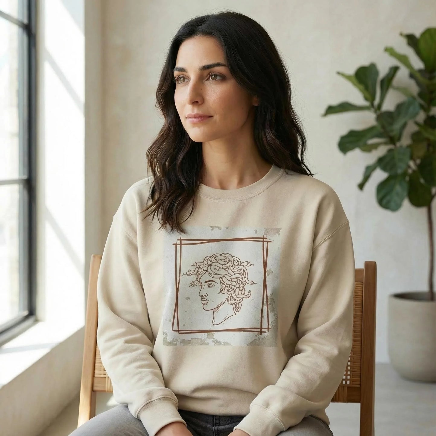 Indoor 3/4 lifestyle view showing Minimal Medusa design on Sand unisex crewneck