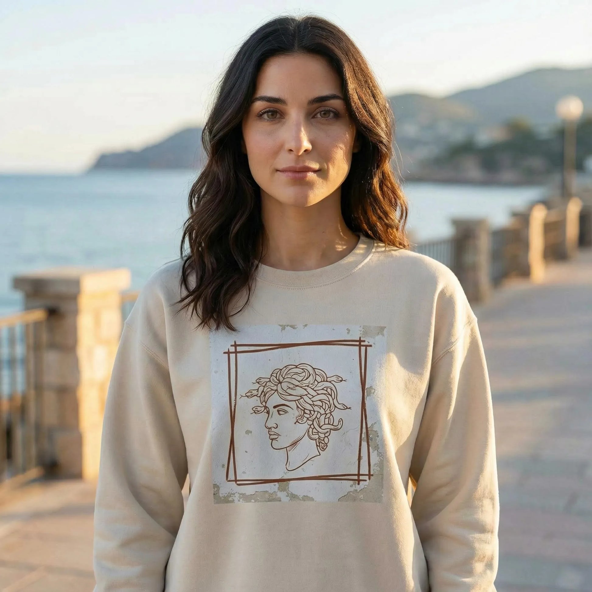 Seaside lifestyle scene with Minimal Medusa design visible on Sand unisex sweatshirt