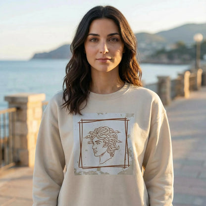 Seaside lifestyle scene with Minimal Medusa design visible on Sand unisex sweatshirt