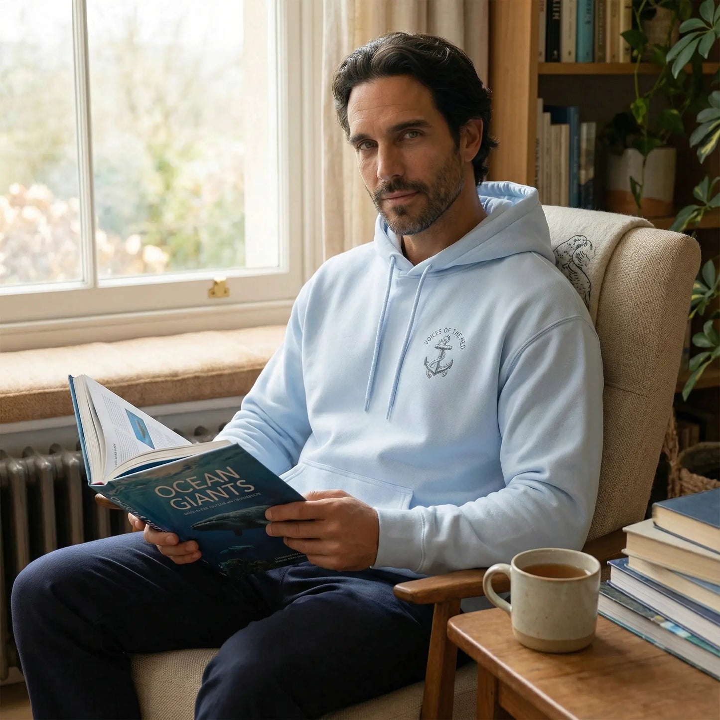 Monk Seal Embrace hoodie worn indoors in a calm setting with front chest glyph visible