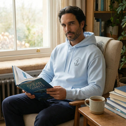 Monk Seal Embrace hoodie worn indoors in a calm setting with front chest glyph visible