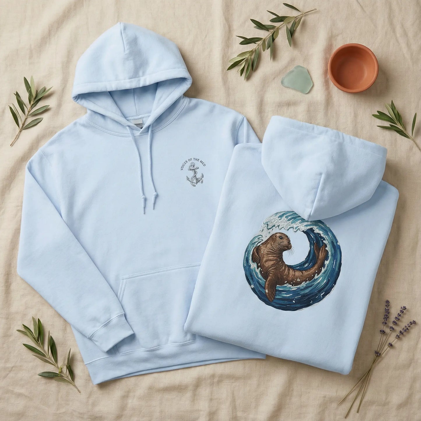Front and back of Monk Seal Embrace hoodie laid out showing chest glyph and monk seal back artwork