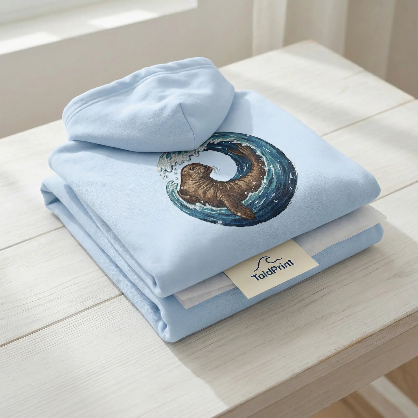 Folded Monk Seal Embrace hoodie with ocean conservation design and minimal ToldPrint packaging
