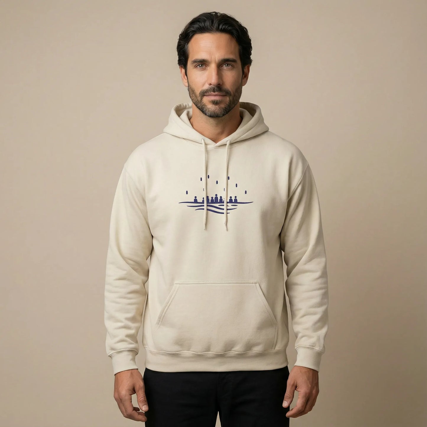 TP:HERO Front studio view of model wearing sand Sea Crossing hoodie with navy embroidered motif on chest.