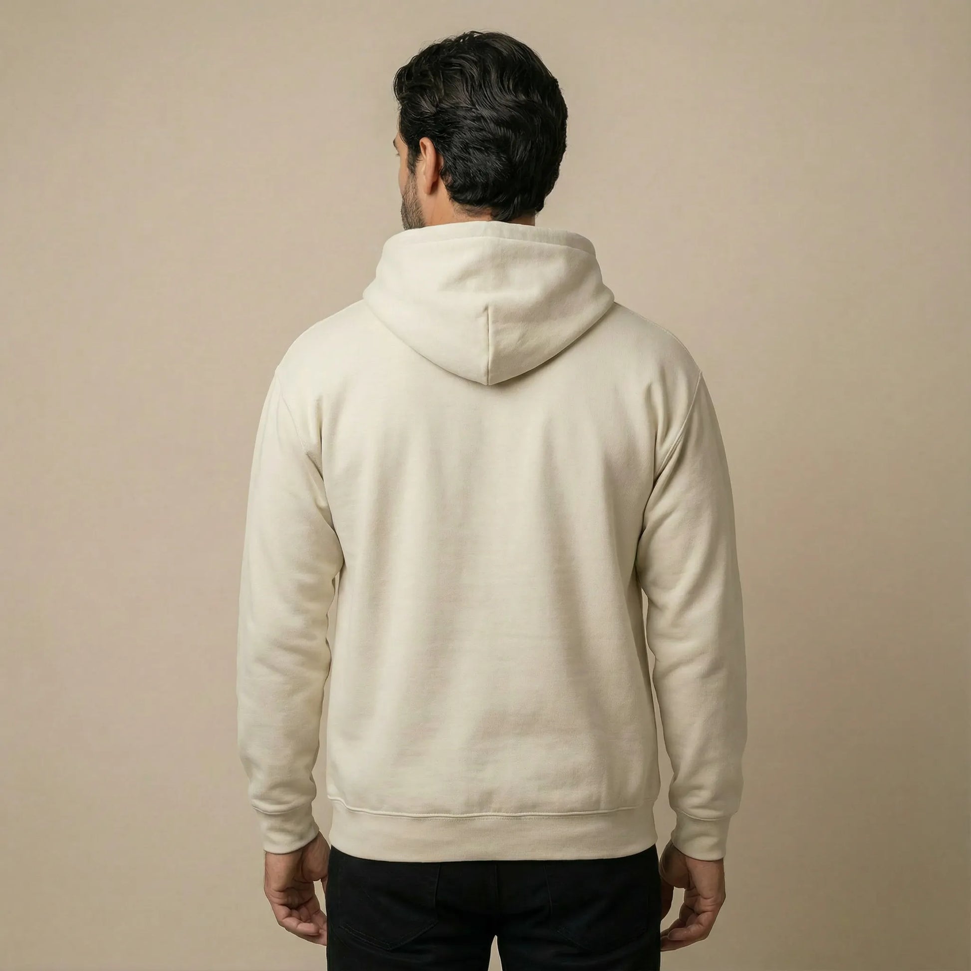 Back studio view of model wearing sand Sea Crossing hoodie showing a plain back with no design.