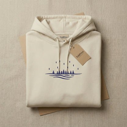 Folded sand Sea Crossing hoodie with ToldPrint label and navy embroidery visible on the top fold.