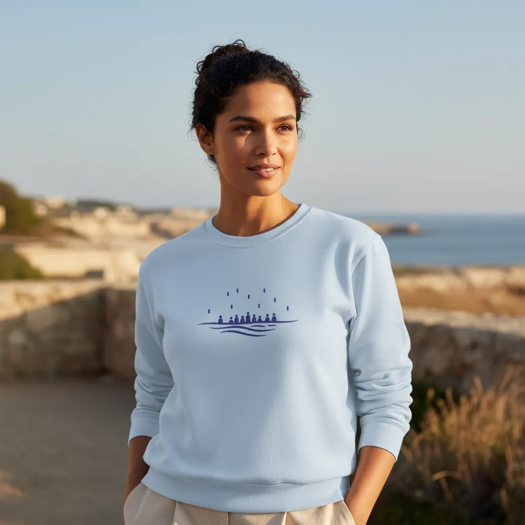 Light blue embroidered sweatshirt worn outdoors in soft Mediterranean light, minimalist sea motif, ethical apparel