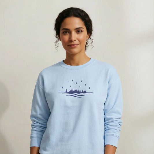 TP:HERO Front view of light blue Gildan 18000 crewneck with minimalist embroidered sea design, worn by model in studio