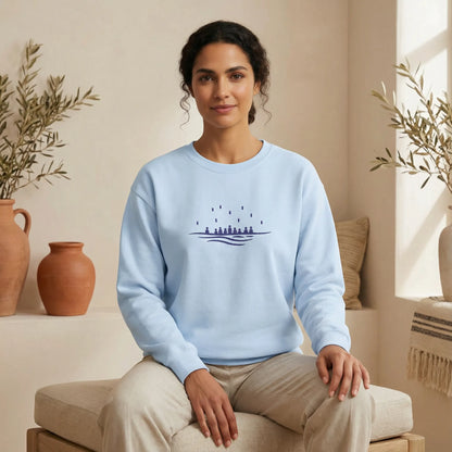 Light blue embroidered crewneck sweatshirt worn by model in relaxed seated studio pose, minimalist sea-inspired design, ToldPrint