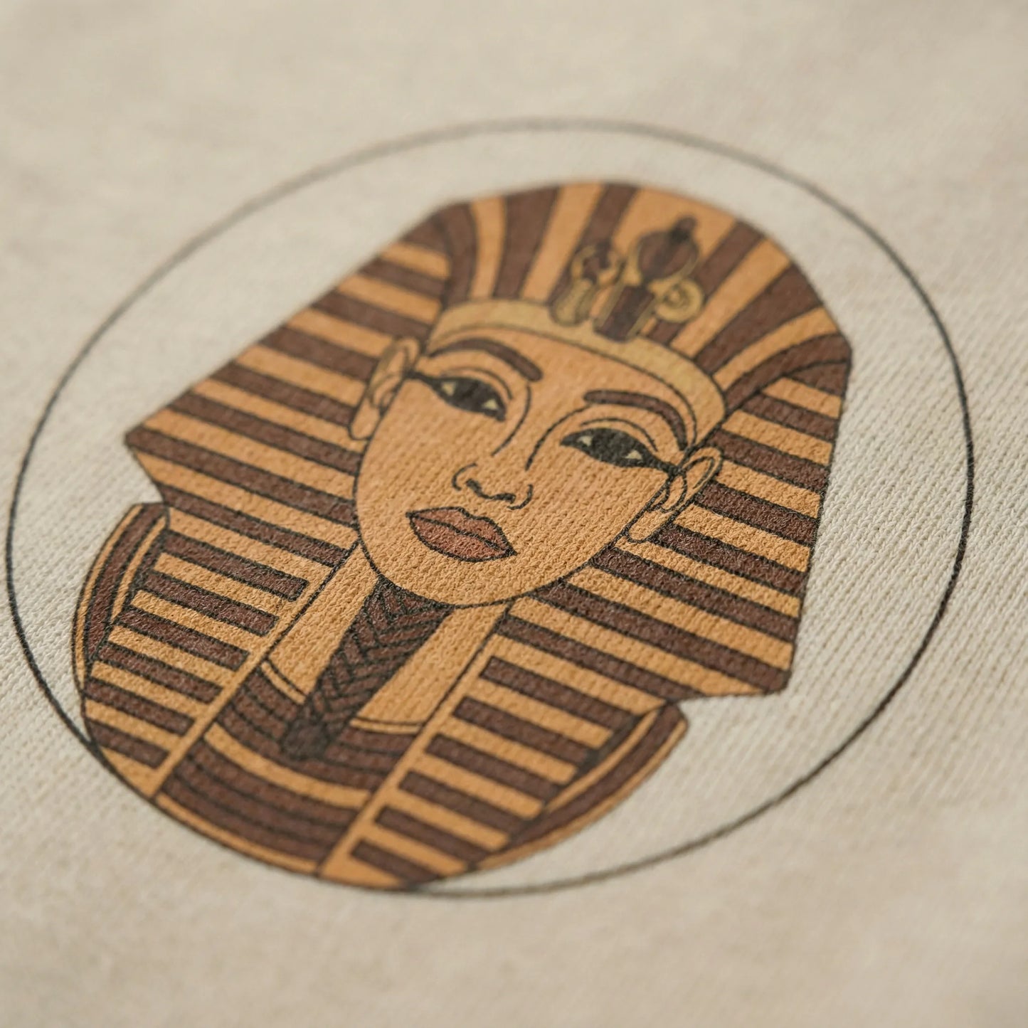 Close up of Sphinx graphic print on hoodie fabric, showing detailed Egyptian head inside circular badge