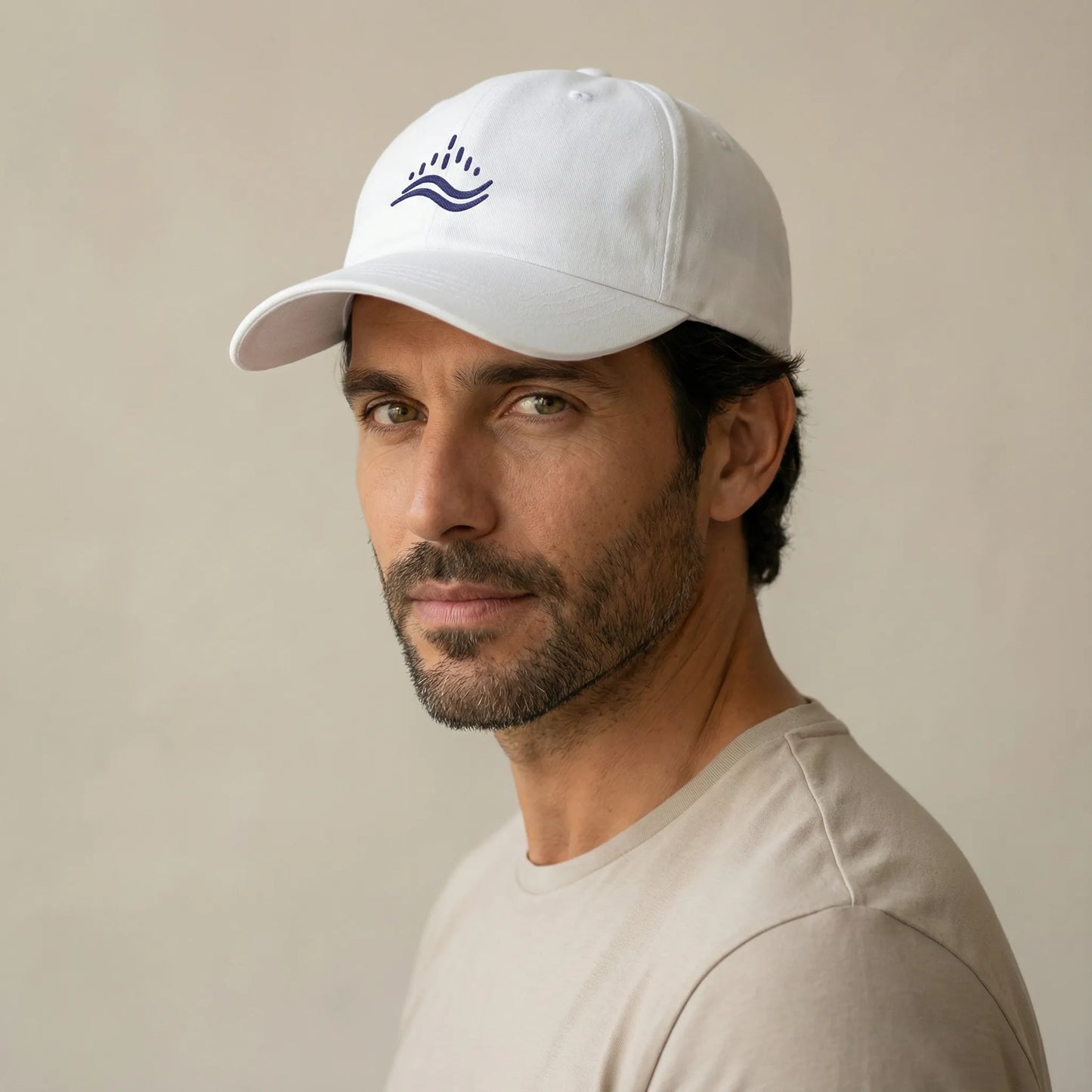 Three-quarter angle of white unstructured dad cap on model, curved visor and navy wave emblem visible, studio lighting.
