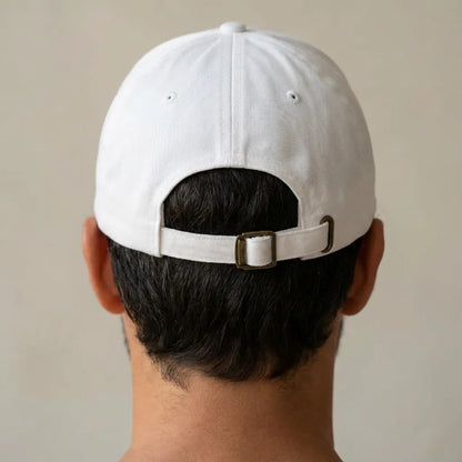 Back detail of white dad cap with adjustable strap and metal buckle, clean studio close-up, unstructured cotton cap.