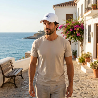 White cotton dad cap with navy wave embroidery worn outdoors in Mediterranean light, relaxed casual look, low profile cap.