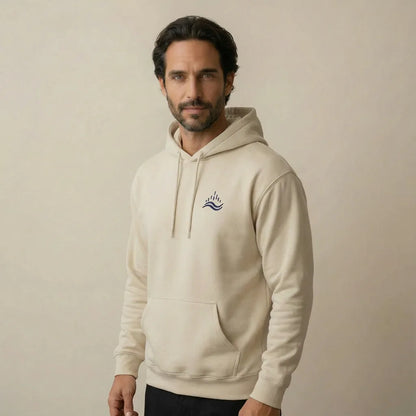 Studio lifestyle view of a model wearing the sand waves emblem hoodie, back turned slightly so the left chest embroidery is still visible.