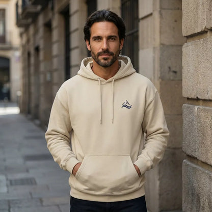 Urban street-style scene with a model wearing the sand waves emblem hoodie, navy embroidery visible on the left chest.