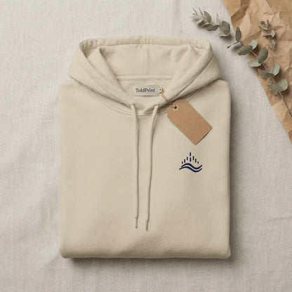 Folded sand waves emblem hoodie in a flat lay with ToldPrint label and simple tag, showing the navy chest embroidery.