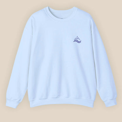 Light blue unisex sweatshirt with navy waves emblem embroidered on the left chest, photographed flat in a neutral studio.