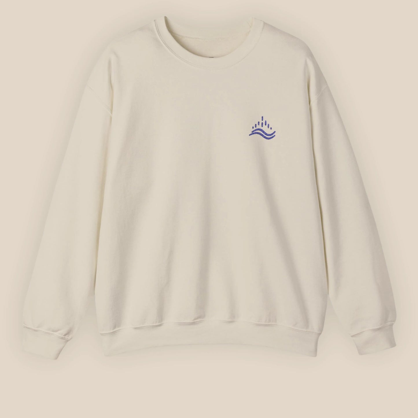 Sand unisex sweatshirt with navy waves emblem embroidered on the left chest, photographed flat in a neutral studio.