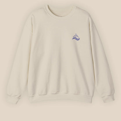 Sand unisex sweatshirt with navy waves emblem embroidered on the left chest, photographed flat in a neutral studio.