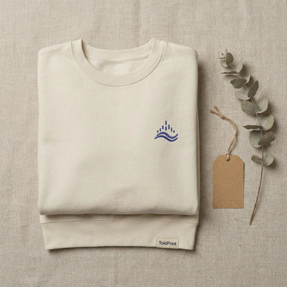 Folded sand waves emblem sweatshirt with ToldPrint label and visible navy embroidery.
