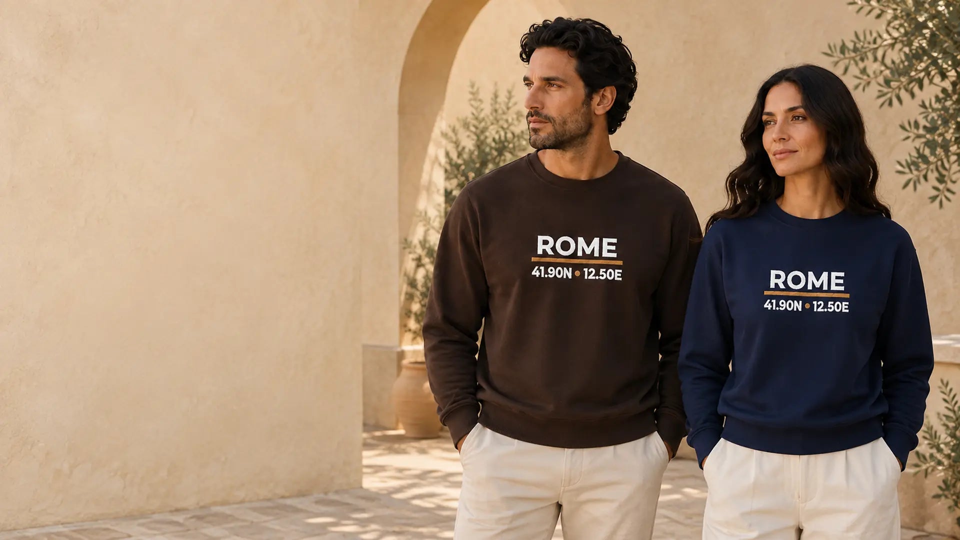 Two models wearing ToldPrint Rome Coordinates embroidered crewneck sweatshirts in a Mediterranean courtyard