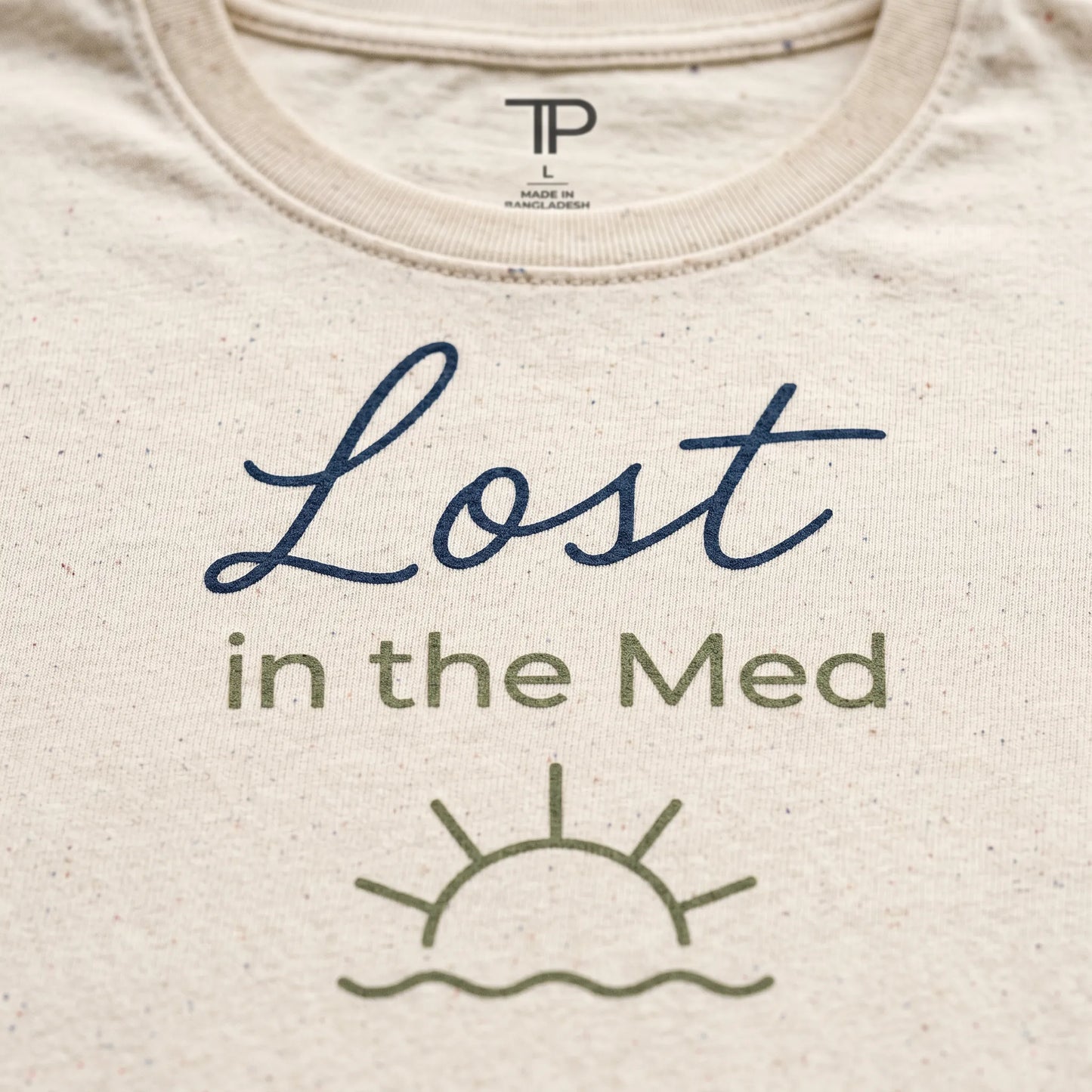 Beige t-shirt with 'Lost in the Med' text and sun graphic on a plain background