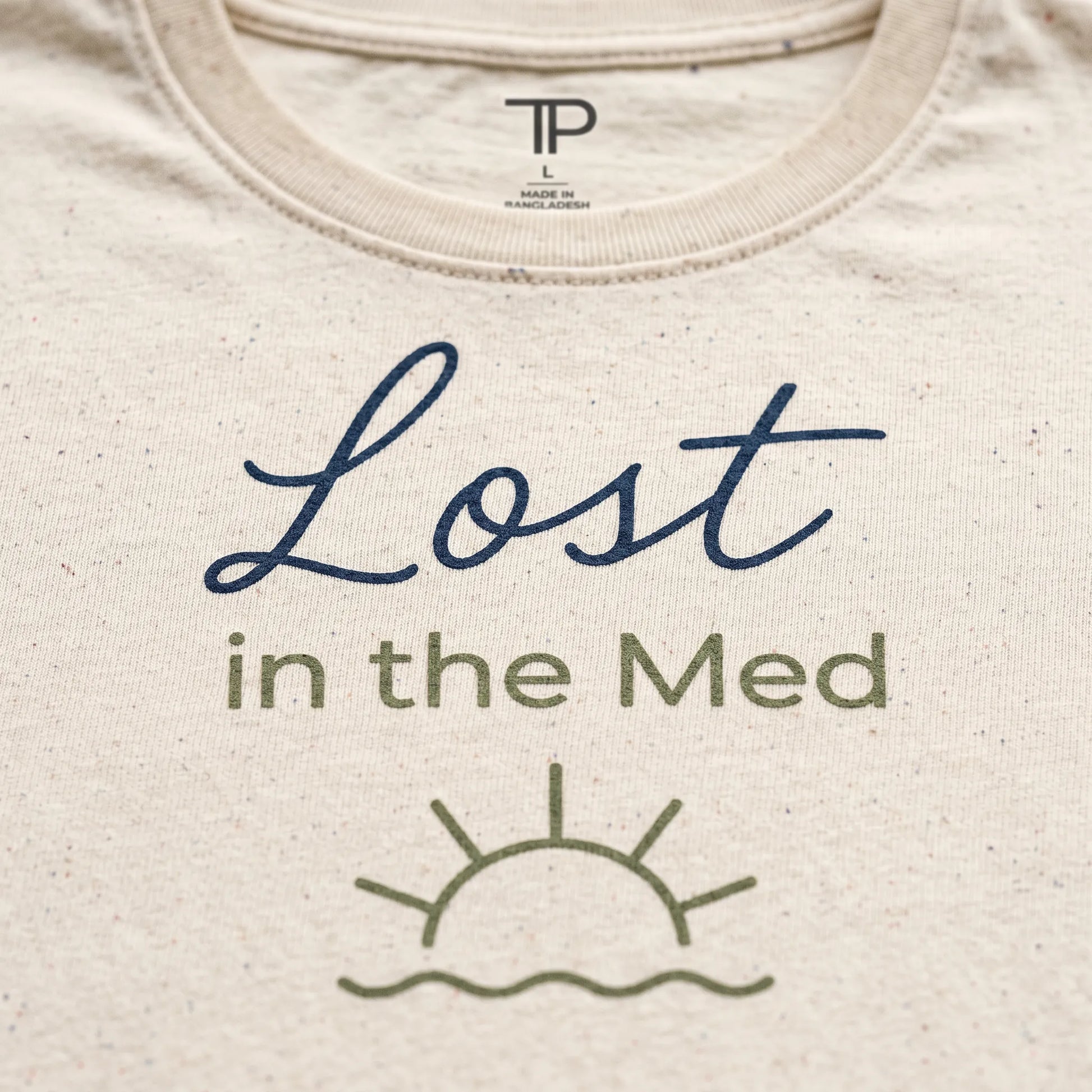 Beige t-shirt with 'Lost in the Med' text and sun graphic on a plain background