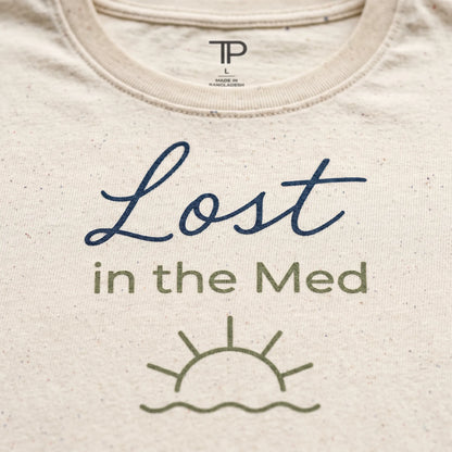 Beige t-shirt with 'Lost in the Med' text and sun graphic on a plain background