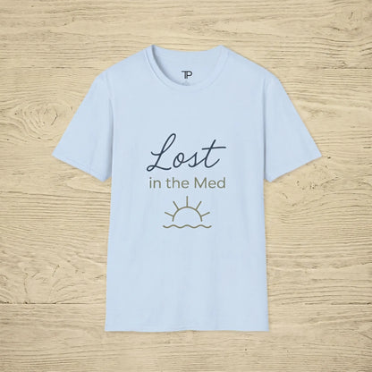 Light blue t-shirt with 'Lost in the Med' text and sun graphic on a wooden surface