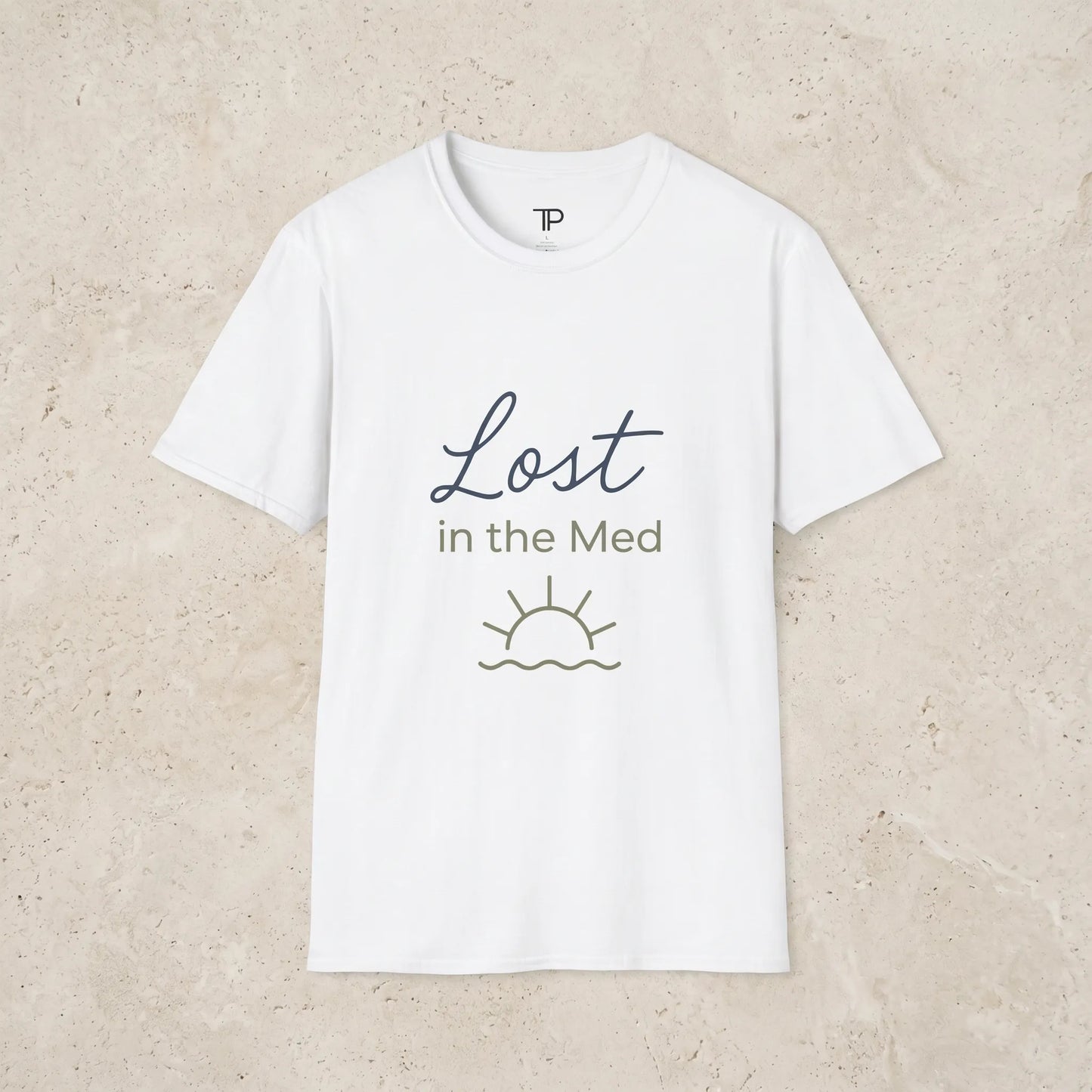 white t-shirt with 'Lost in the Med' text and sun graphic on a light beige background