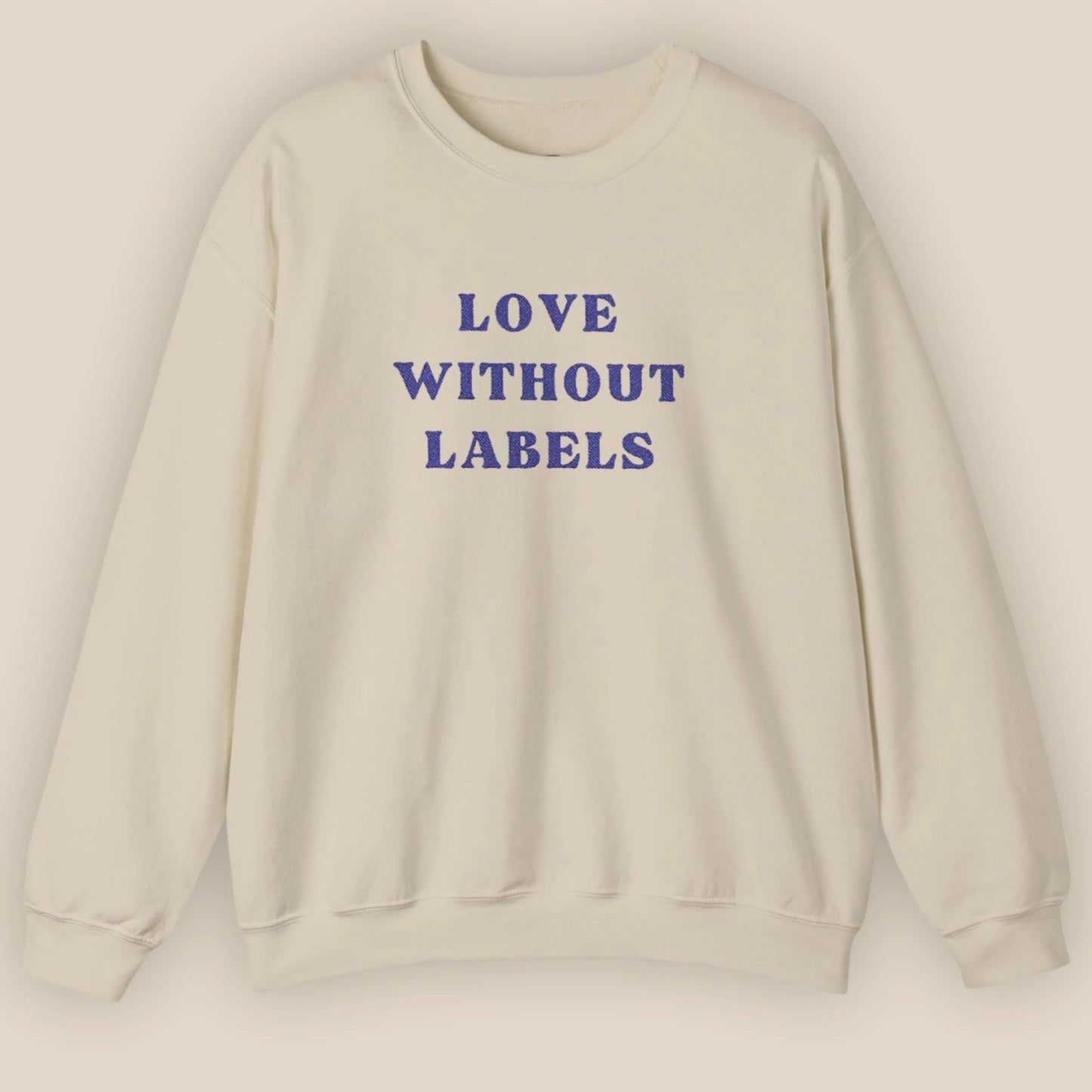 Flat lay of Love Without Labels inclusive slogan embroidered unisex crewneck sweatshirt in sand color by ToldPrint
