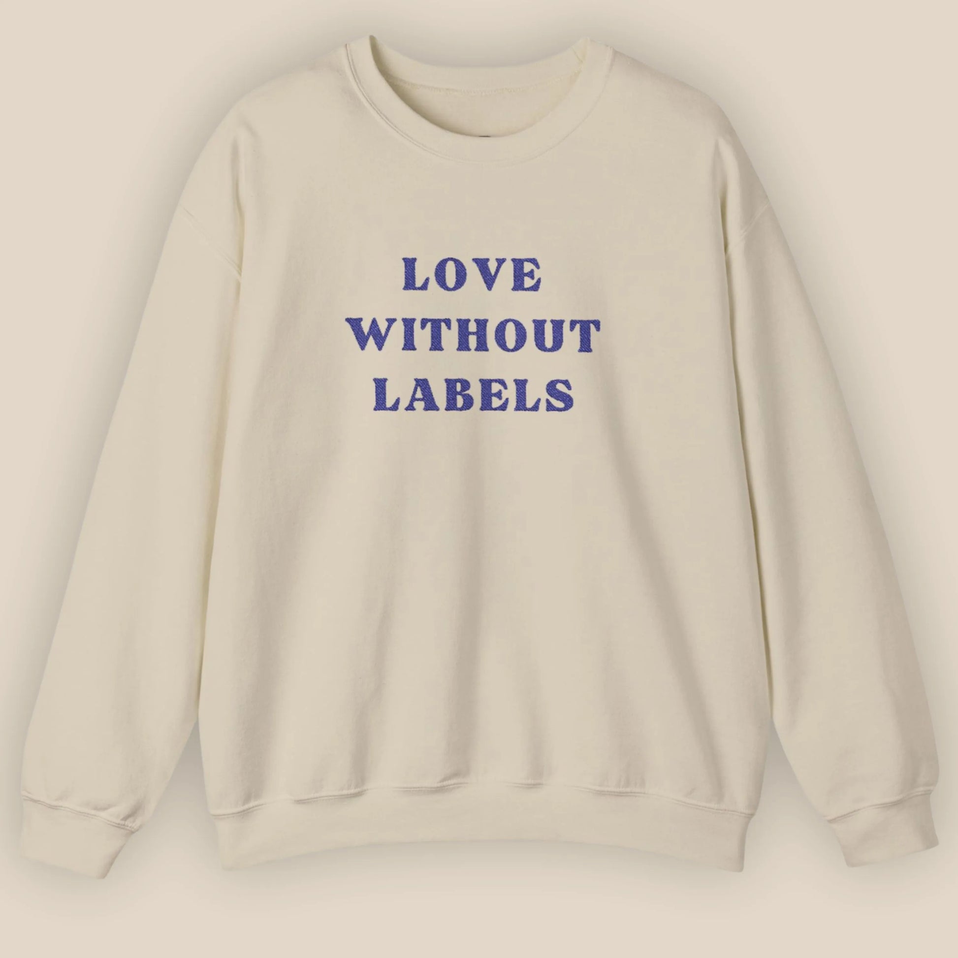 Flat lay of Love Without Labels inclusive slogan embroidered unisex crewneck sweatshirt in sand color by ToldPrint