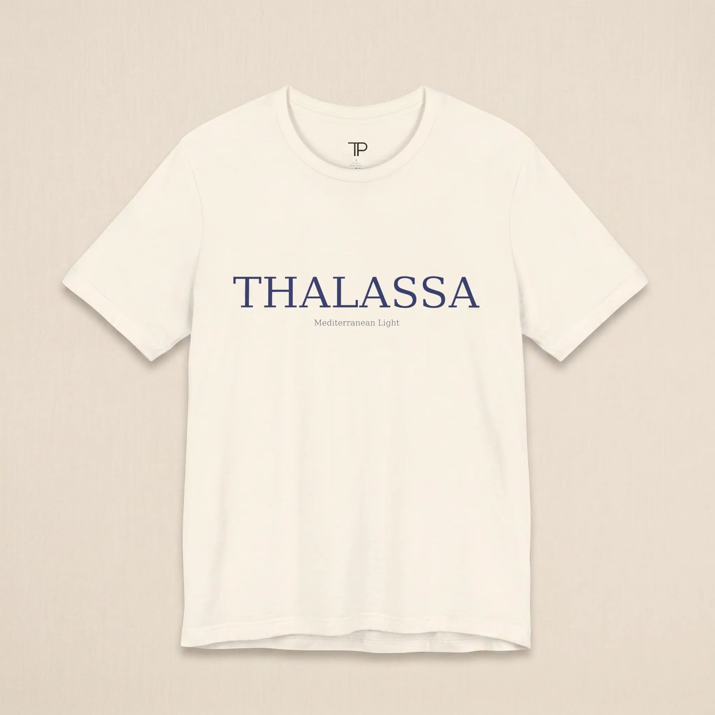 White t-shirt with 'THALASSA' text on a beige background