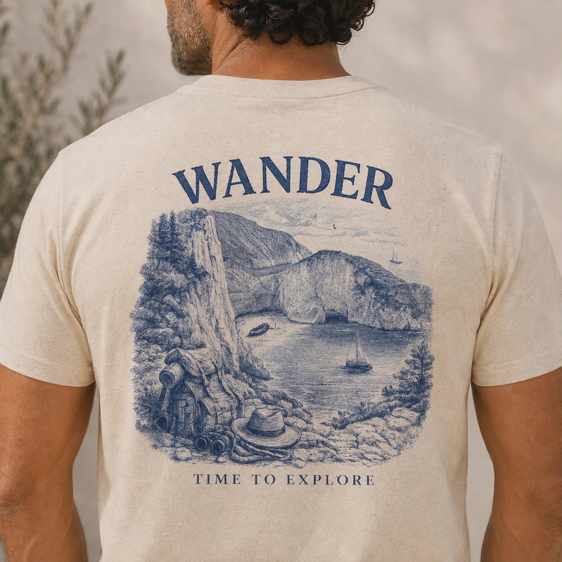 TP HERO: Beige t-shirt with a scenic graphic and 'Wander' text on the back, worn by a person.