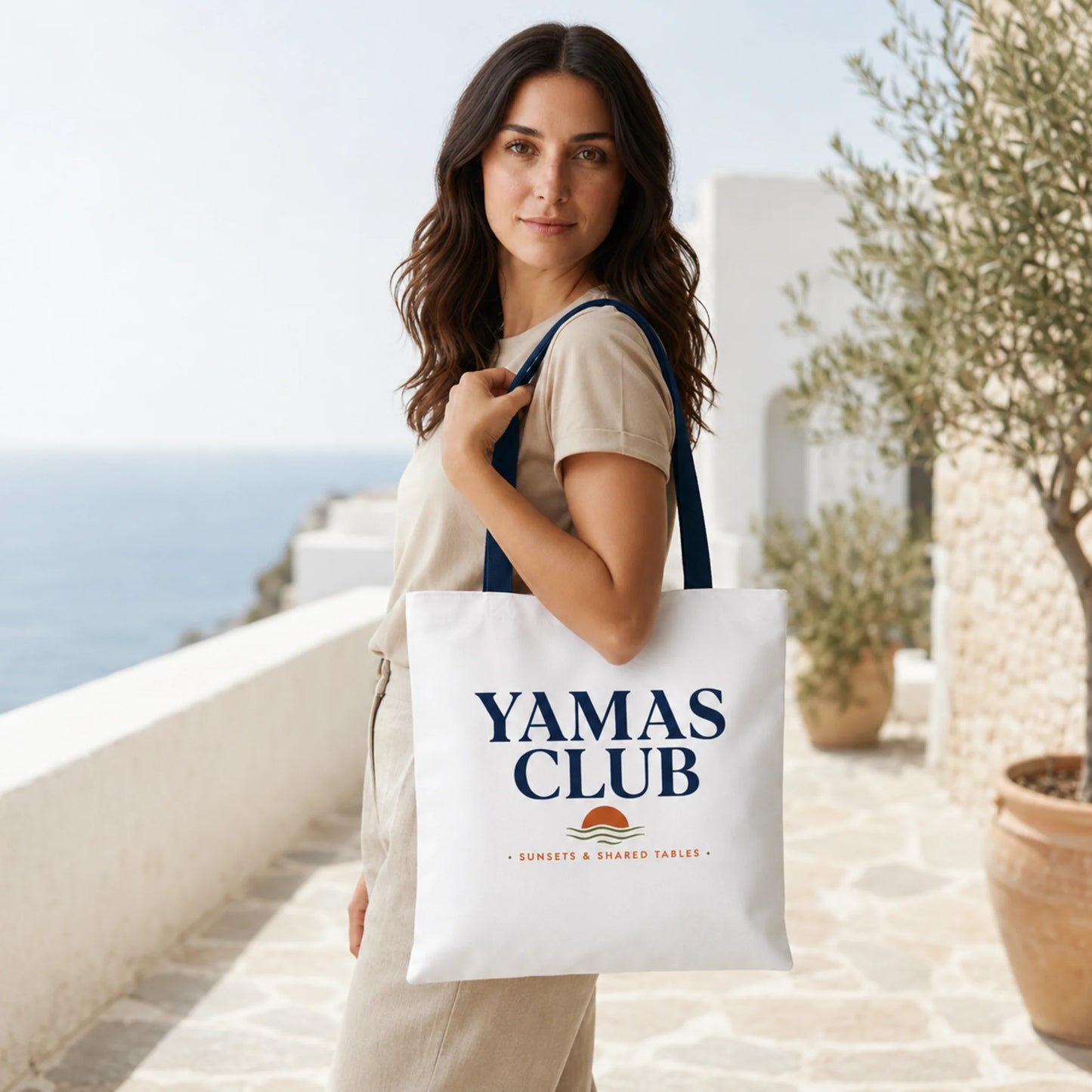 Woman holding a 'Yamas Club' tote bag with a scenic background