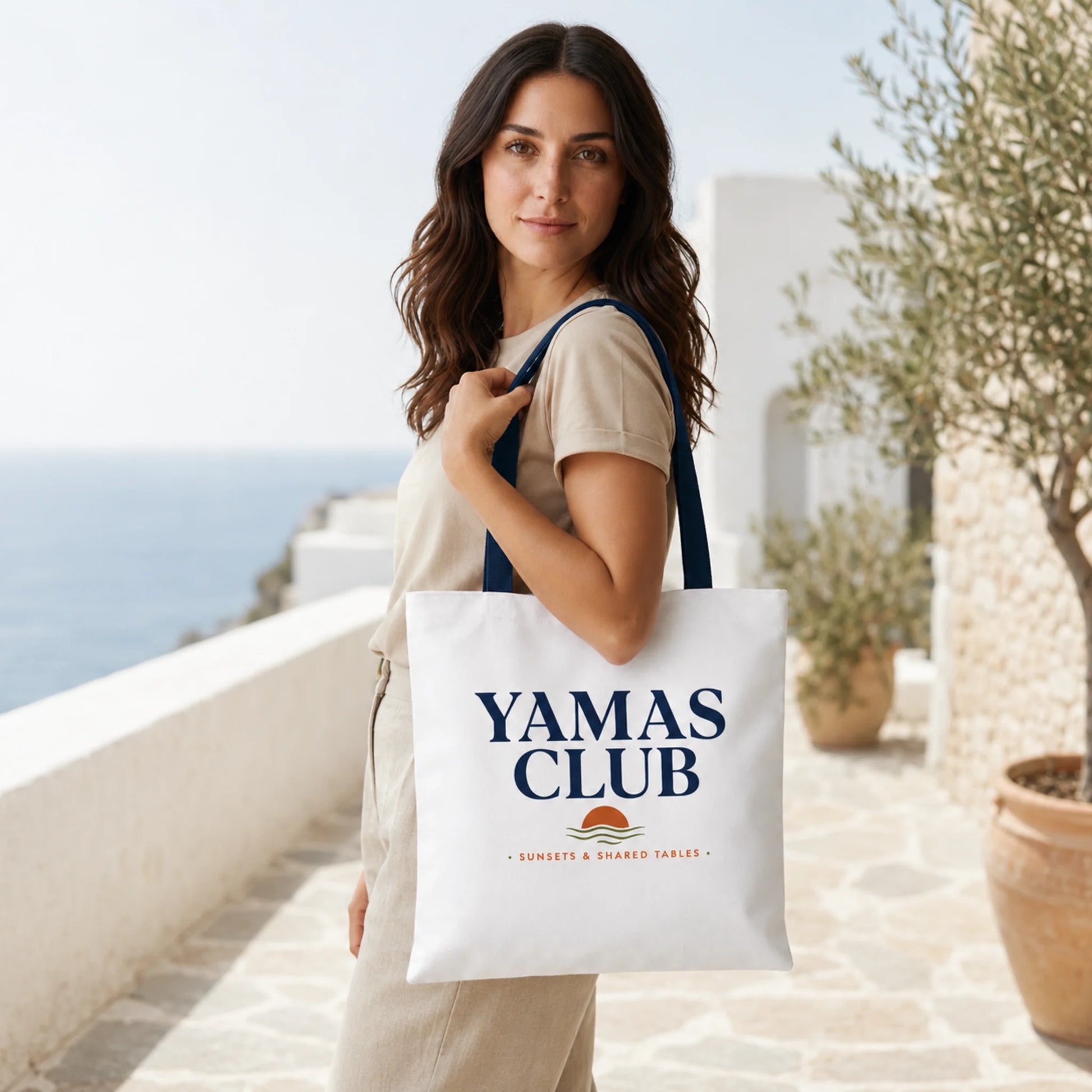 Woman holding a 'Yamas Club' tote bag with a scenic background
