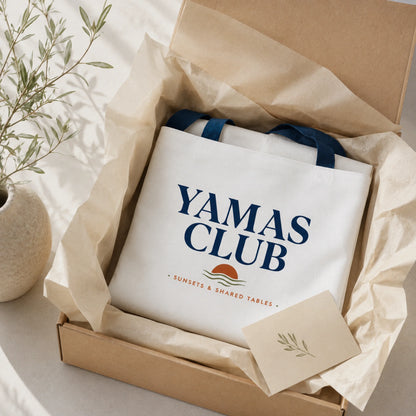 White tote bag with 'Yamas Club' text in a box with brown tissue paper.