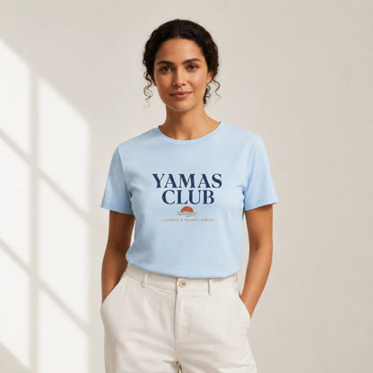 Woman wearing a light blue t-shirt with 'Yamas Club' text, standing against a neutral background
